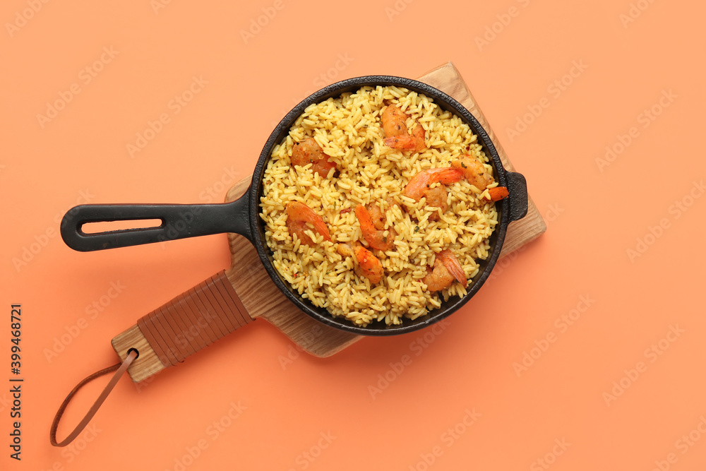 Frying pan with tasty pilaf on color background