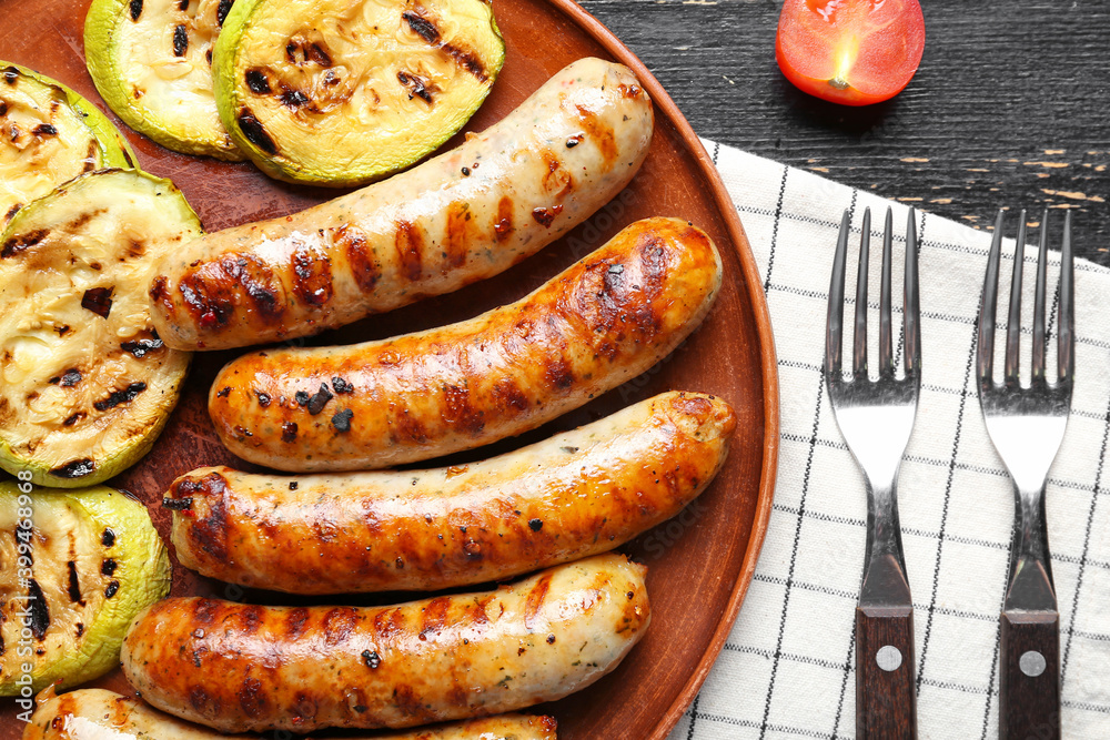 Plate with tasty grilled sausages and vegetables on table, closeup