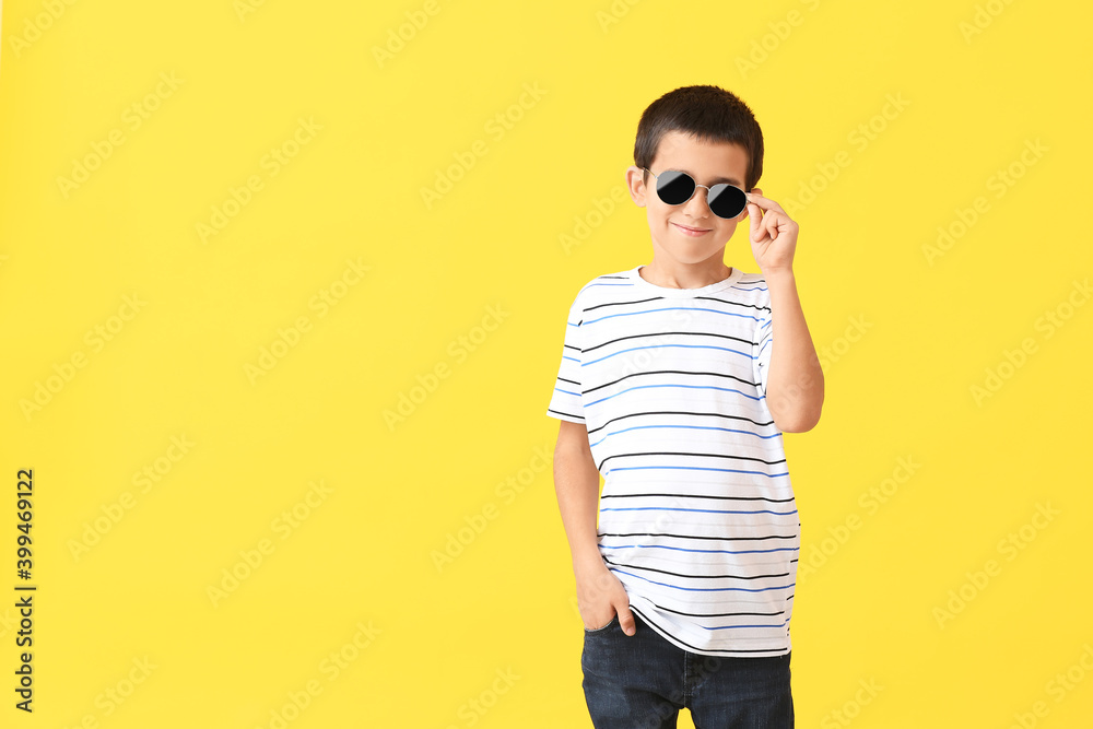 Cute boy wearing stylish sunglasses against color background