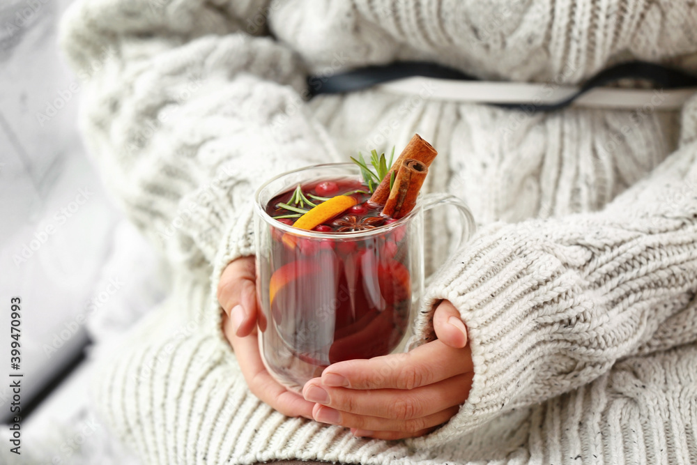 Woman with tasty mulled wine near window in room, closeup