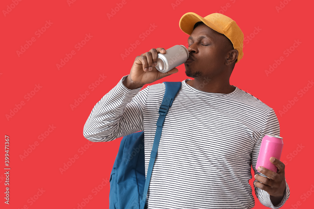 Handsome African-American man with soda on color background