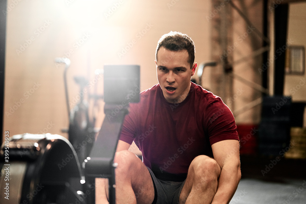 Young man using a rowing machine during a gym workout