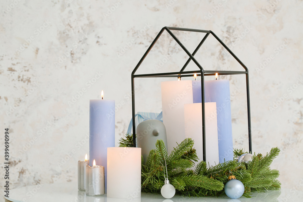 Christmas wreath with burning candles on table in room