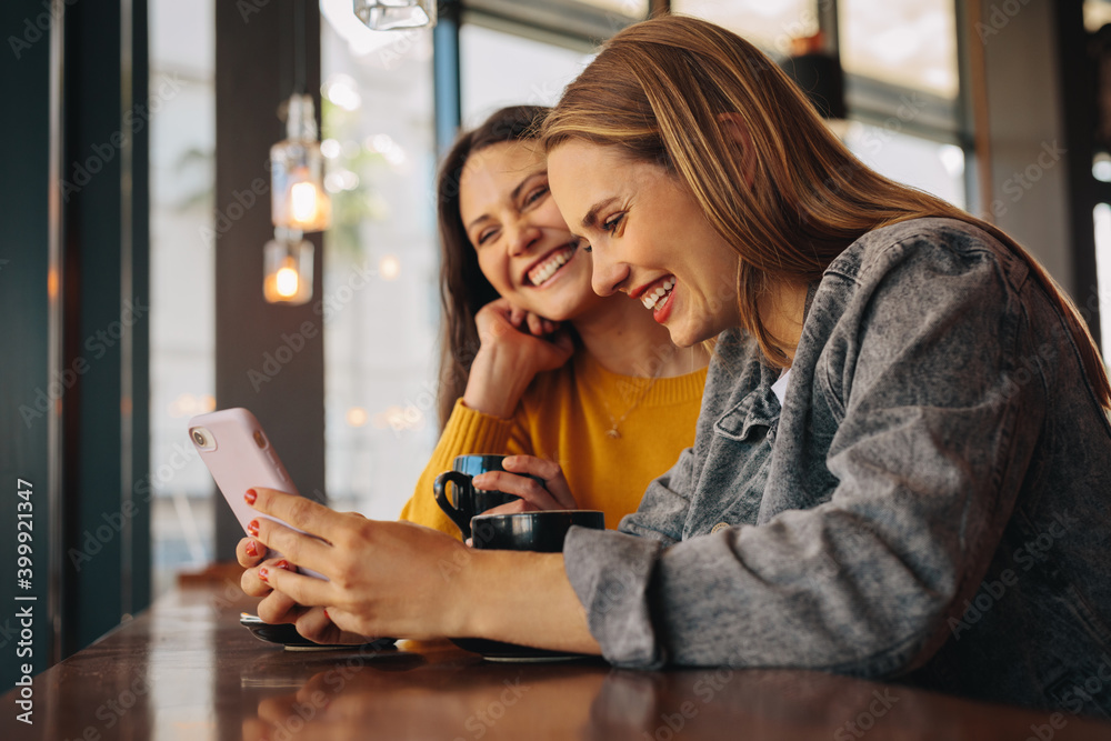 Friends at cafe using phone and smiling