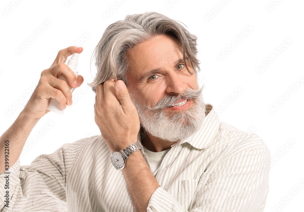 Mature man applying hair spray on white background