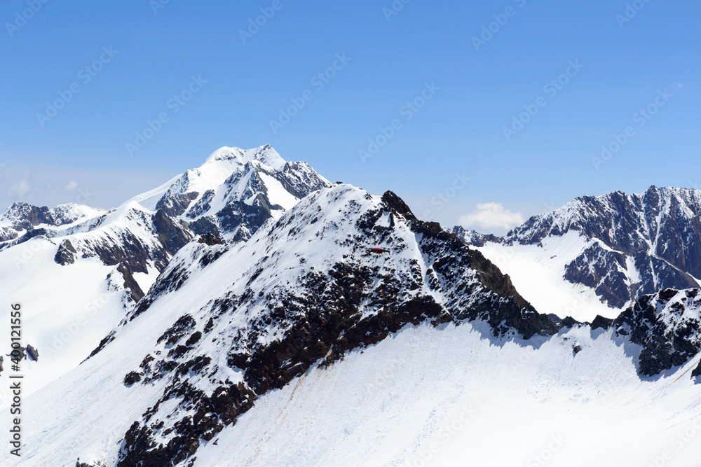 无人机在奥地利蒂罗尔阿尔卑斯山的Wildspitze山前飞行，雪景和蓝天