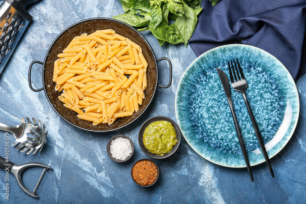 Ingredients for pasta and pesto sauce on color background