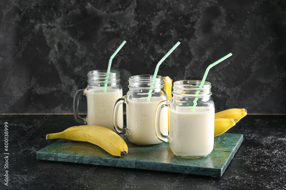 Mason jars of tasty banana smoothie on dark background