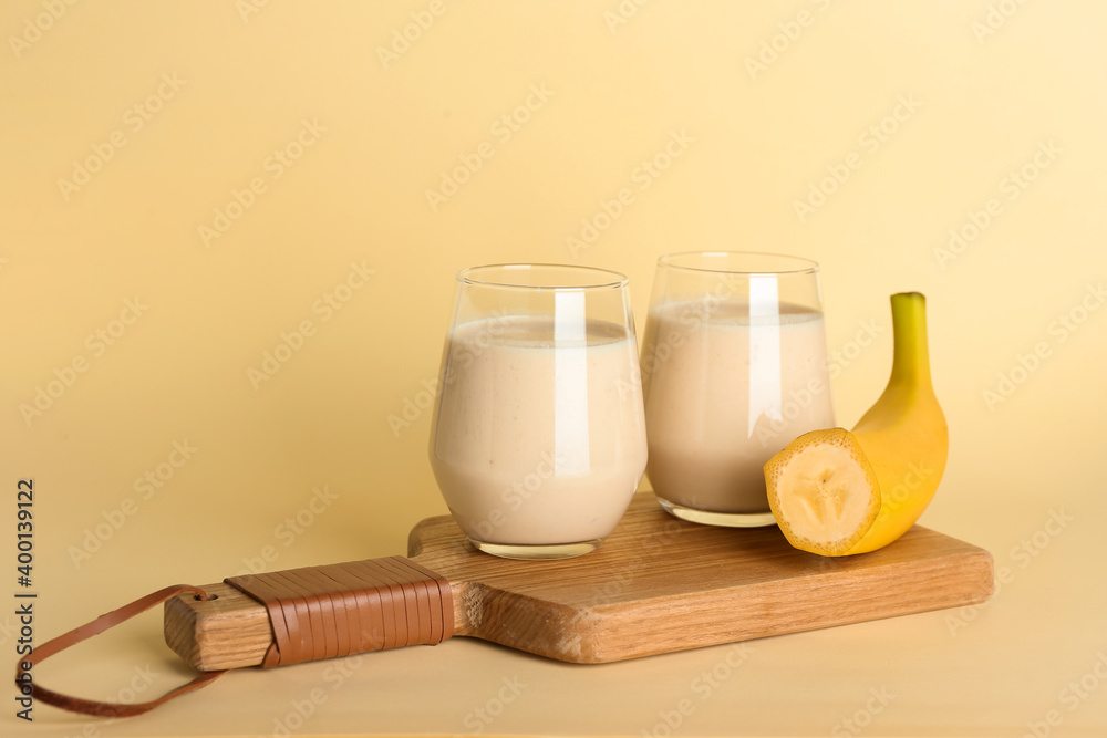 Glasses of tasty banana smoothie on color background