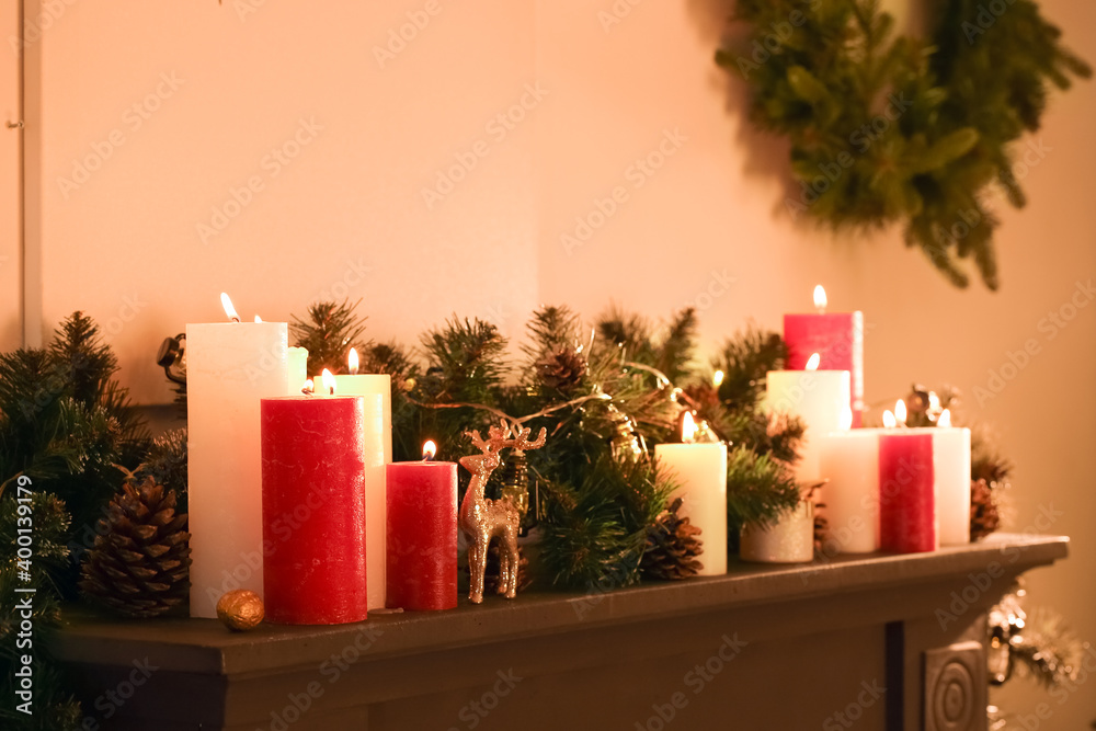 Burning candles on mantelpiece decorated for Christmas