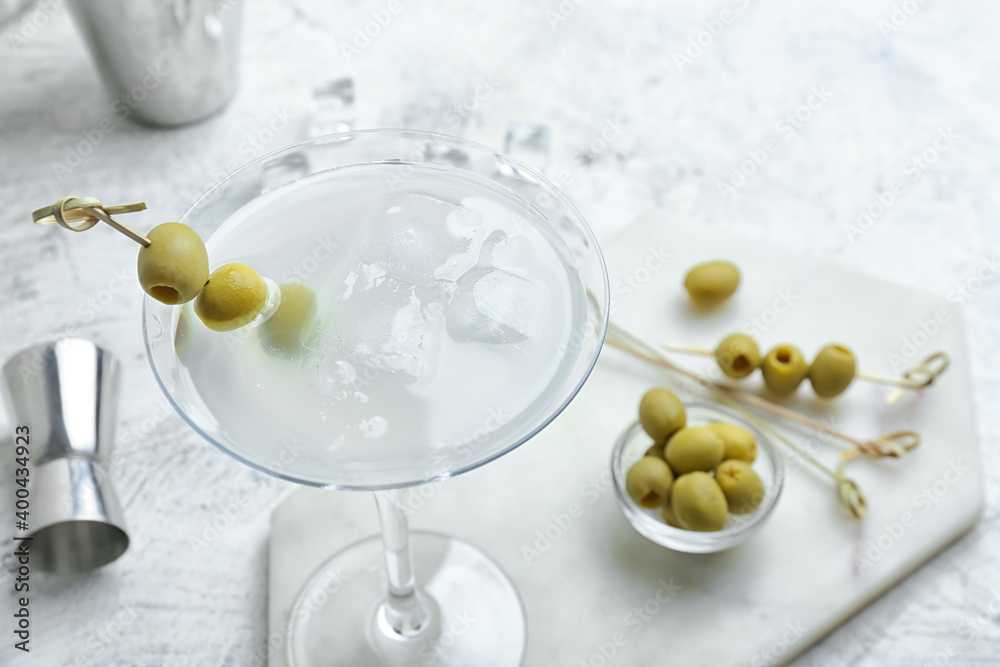 Glass of tasty martini with olives on light background