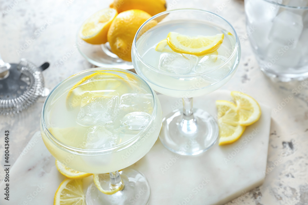 Glasses of tasty martini with lemon on light background