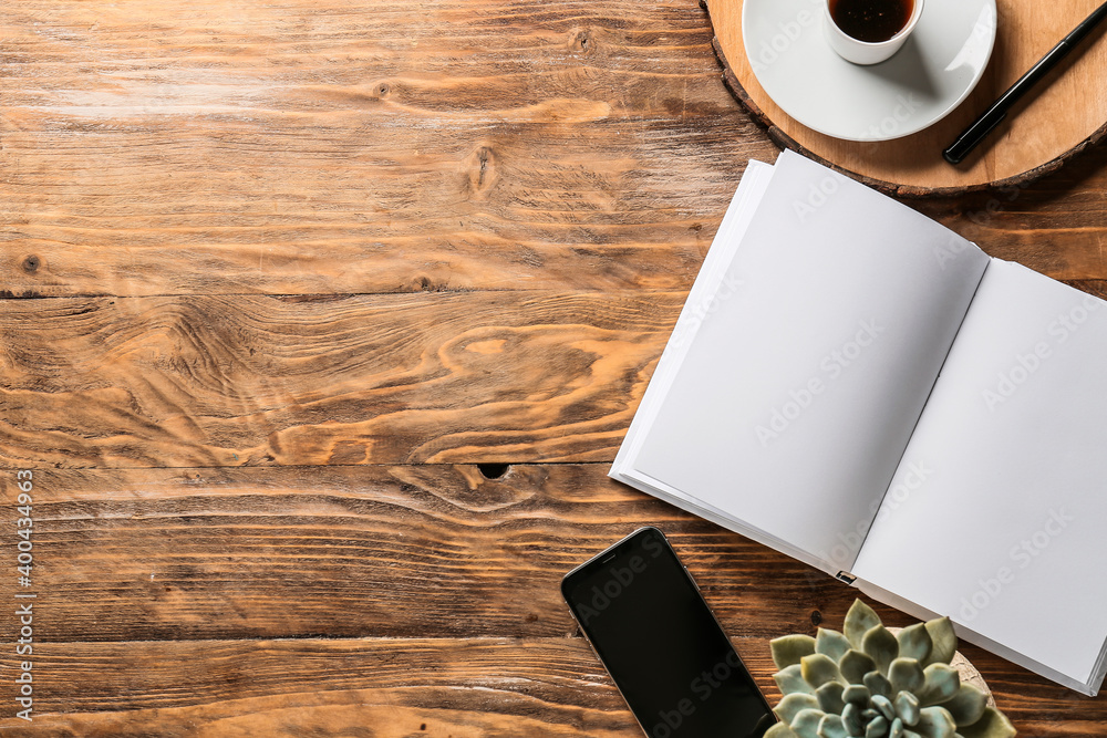 Composition with blank book and phone on wooden table