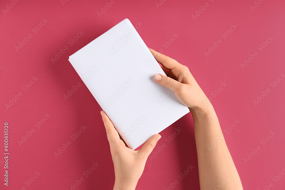 Female hands with blank book on color background