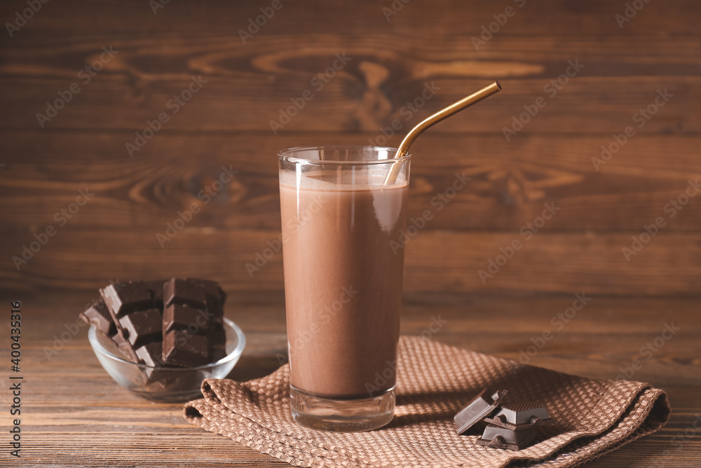 Glass of aromatic chocolate milk on wooden background