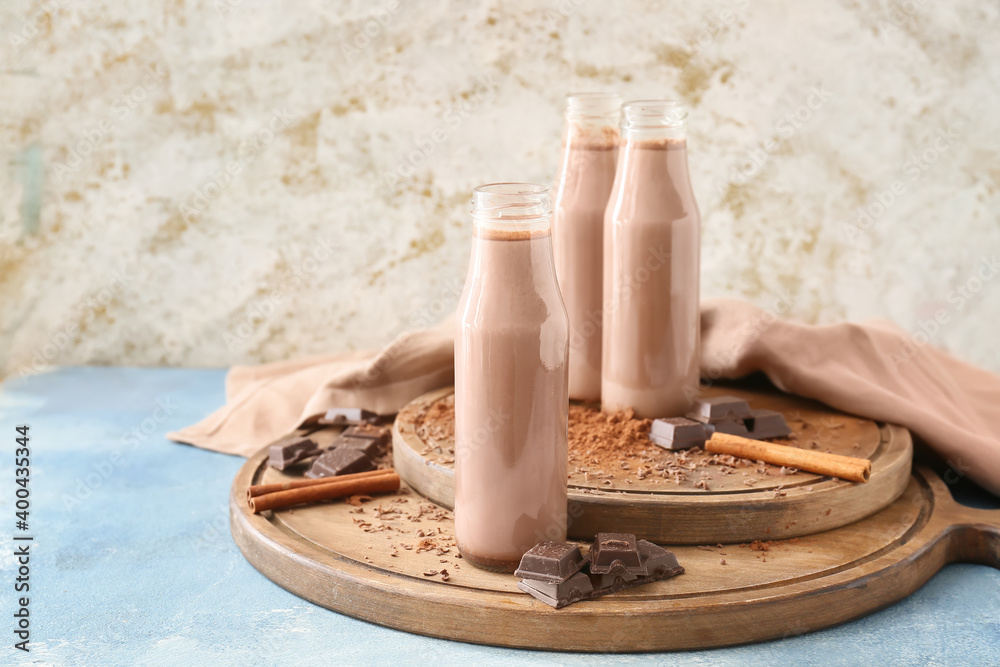 Wooden board with bottles of aromatic chocolate milk on table