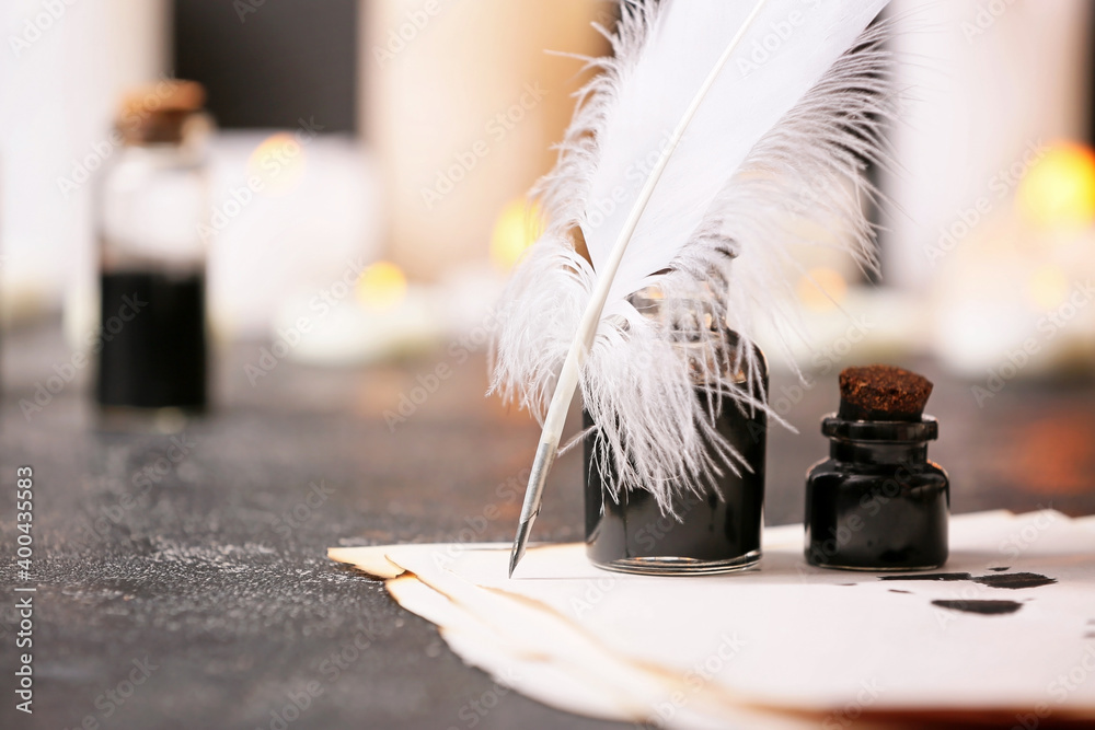 Feather pen, paper sheet and inkwells on table