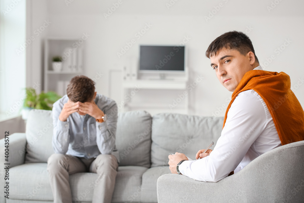 Psychologist working with teenage boy in office