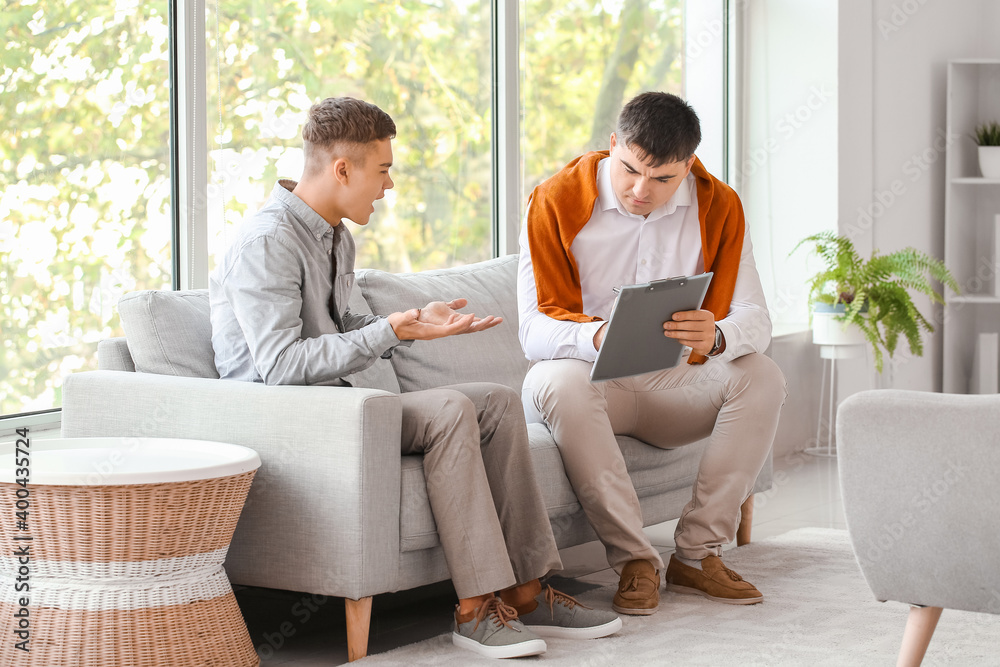 Psychologist working with teenage boy in office