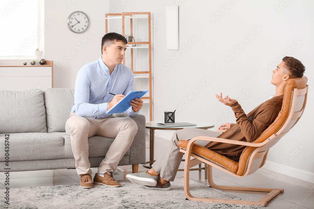 Psychologist working with teenage boy in office