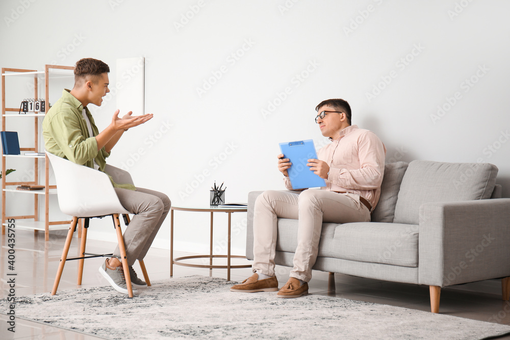 Psychologist working with teenage boy in office