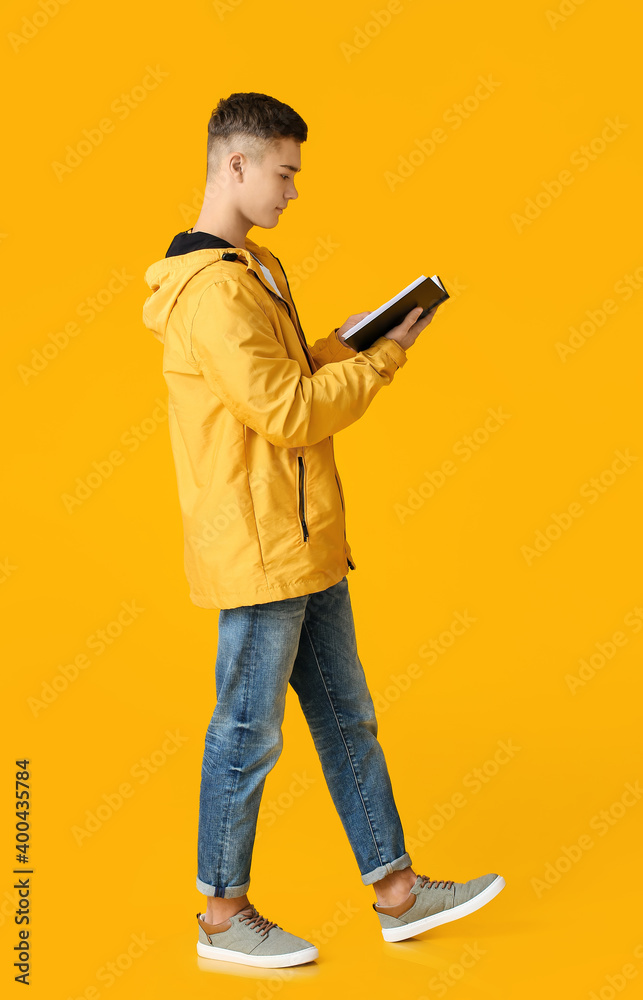 Teenage boy with book on color background