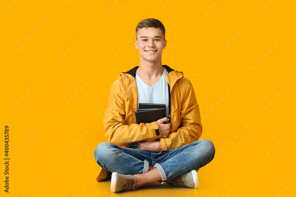 Teenage boy with books on color background