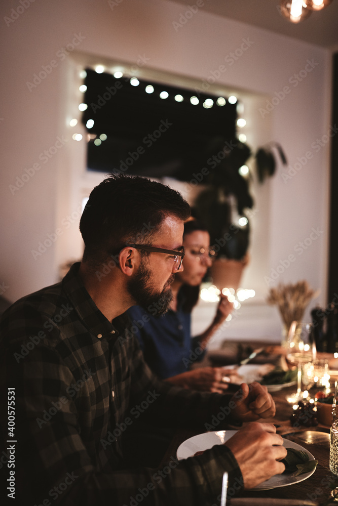 年轻人与朋友在烛光餐桌旁共进晚餐