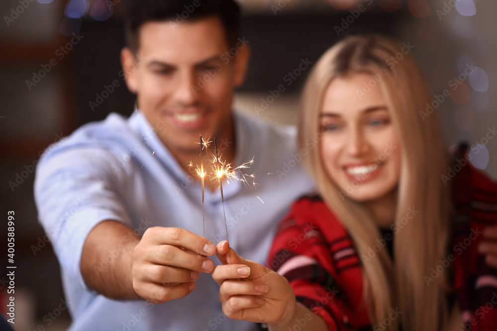 Happy young couple with sparklers celebrating Christmas at home