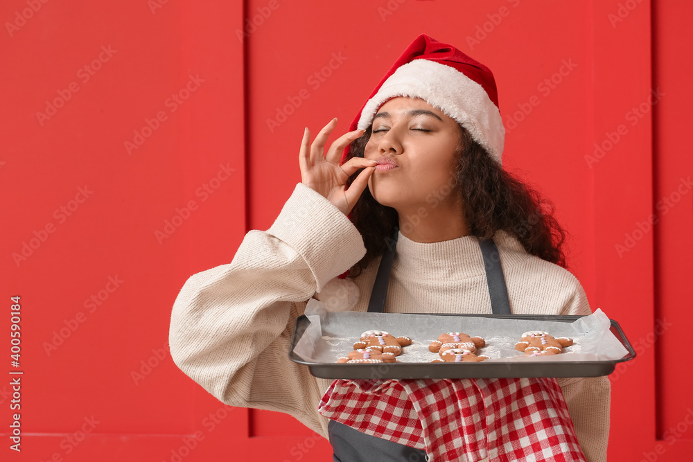 戴着圣诞帽的漂亮年轻女子，彩色背景上有美味的姜饼饼干