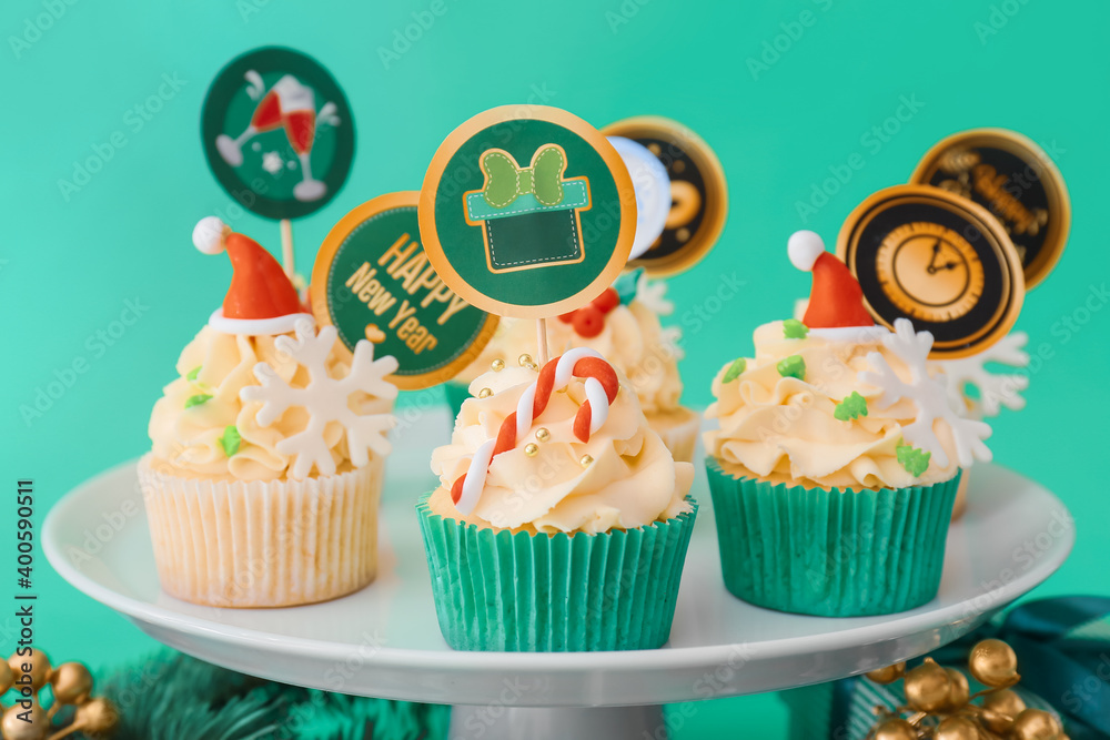 Dessert stand with tasty Christmas cupcakes on color background