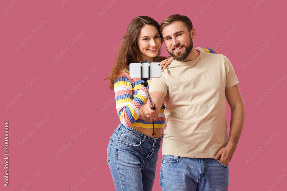 Young couple taking selfie on color background