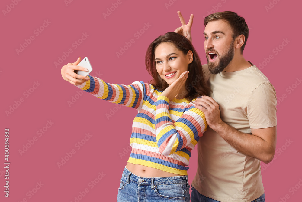 Young couple taking selfie on color background