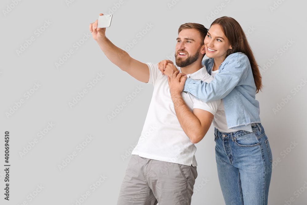 Young couple taking selfie on light background