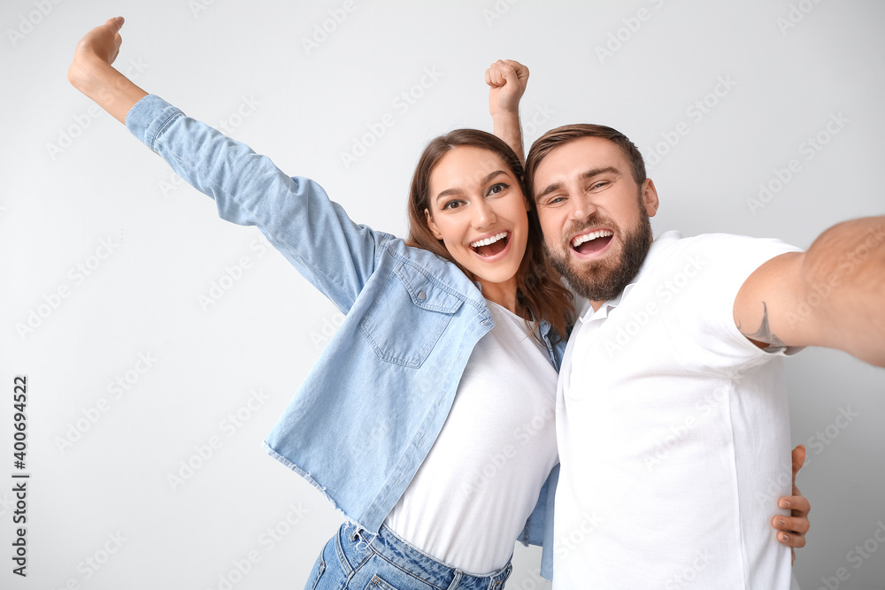 Young couple taking selfie on light background