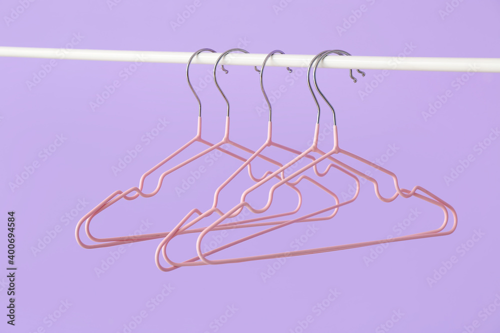 Rack with clothes hangers on color background