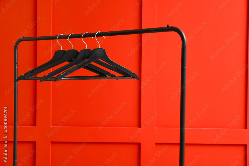 Rack with clothes hangers on color background