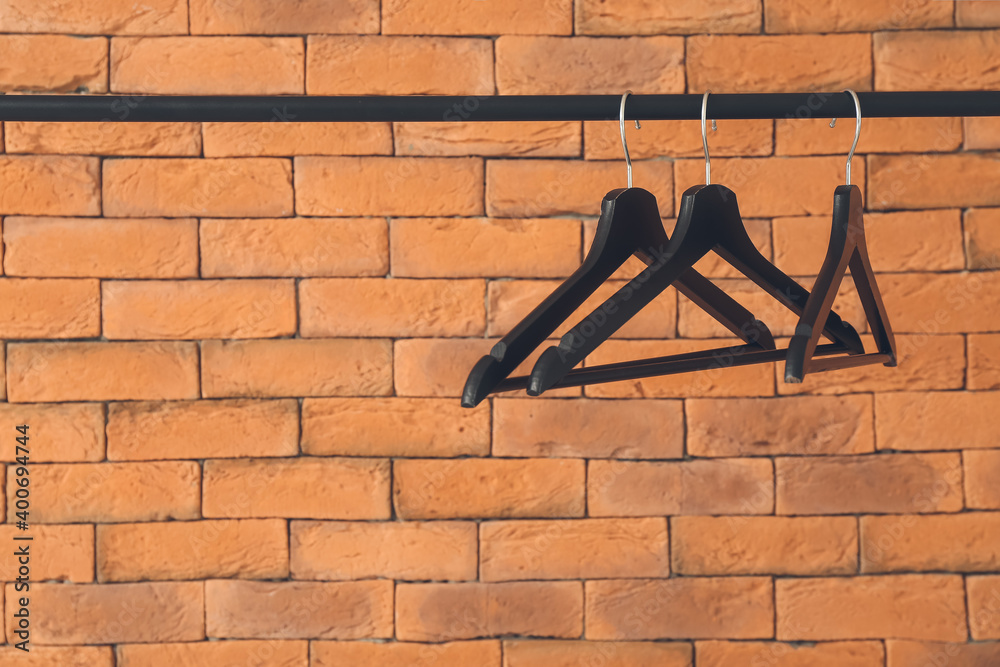 Rack with clothes hangers near brick wall