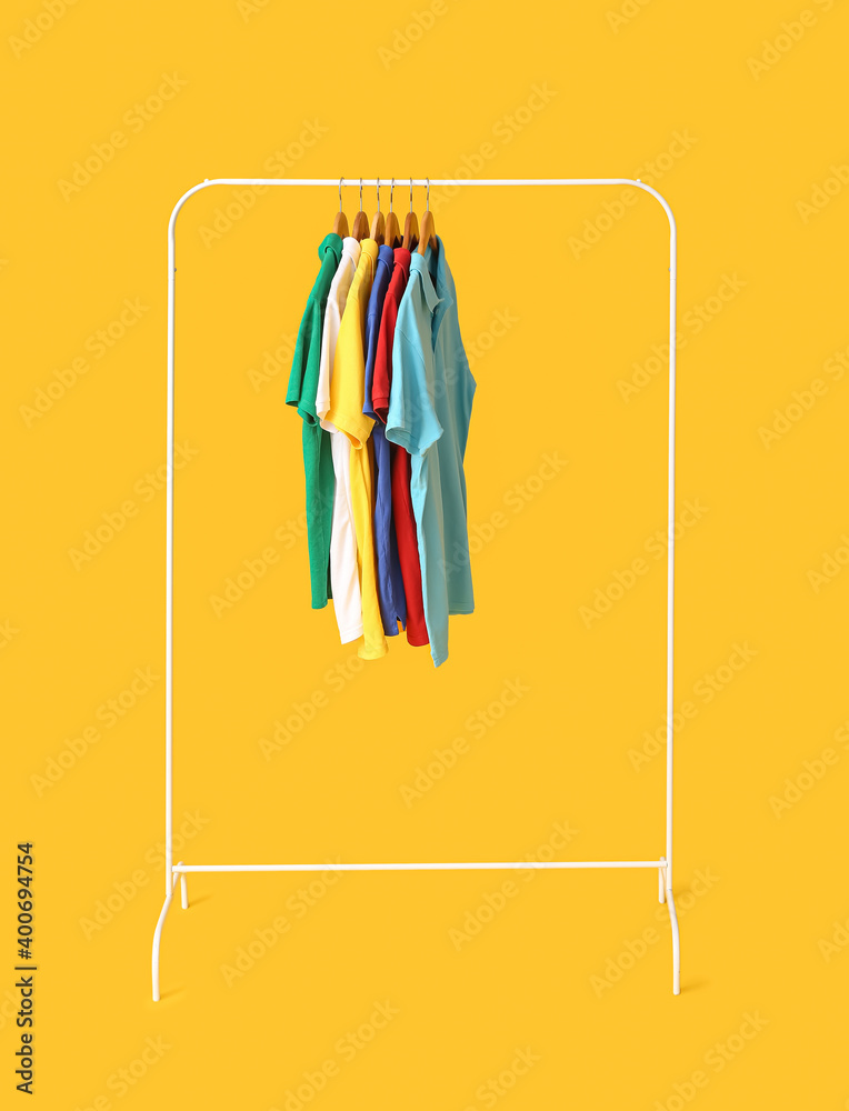 Rack with clothes on color background