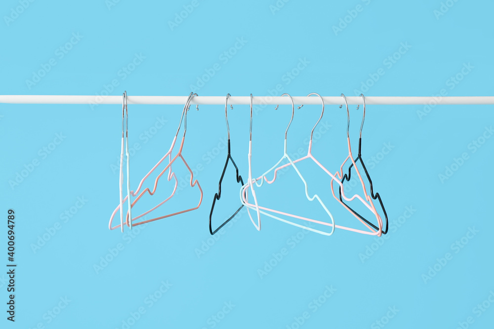 Rack with clothes hangers on color background