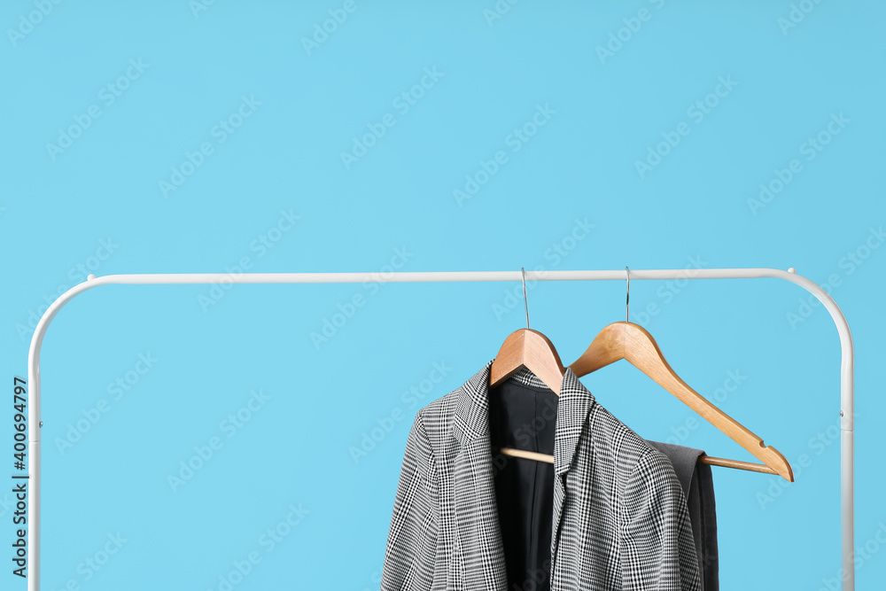 Rack with clothes on color background