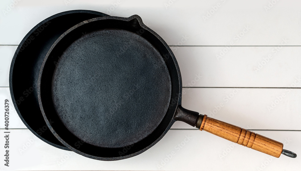 The two cast iron frying pans over the background of whiteboards. 
