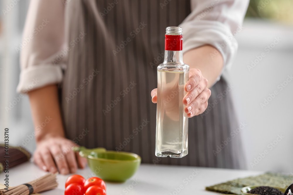 Woman with bottle of rice vinegar in kitchen