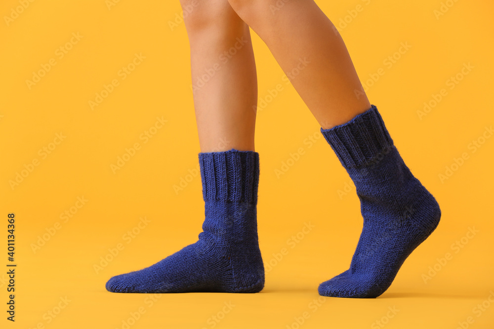 Legs of young woman in socks on color background