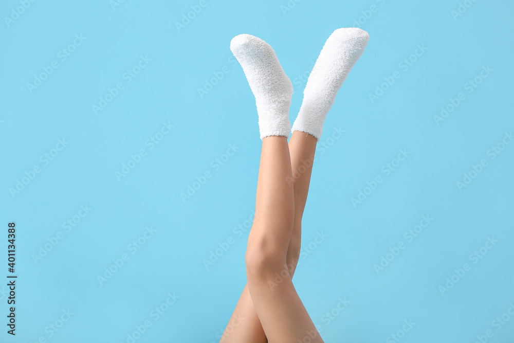 Legs of young woman in socks on color background