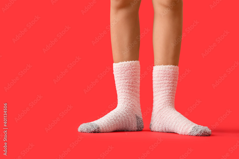 Legs of young woman in socks on color background