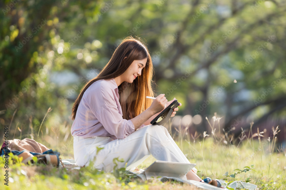 Asian female students studying online She is sitting outdoors