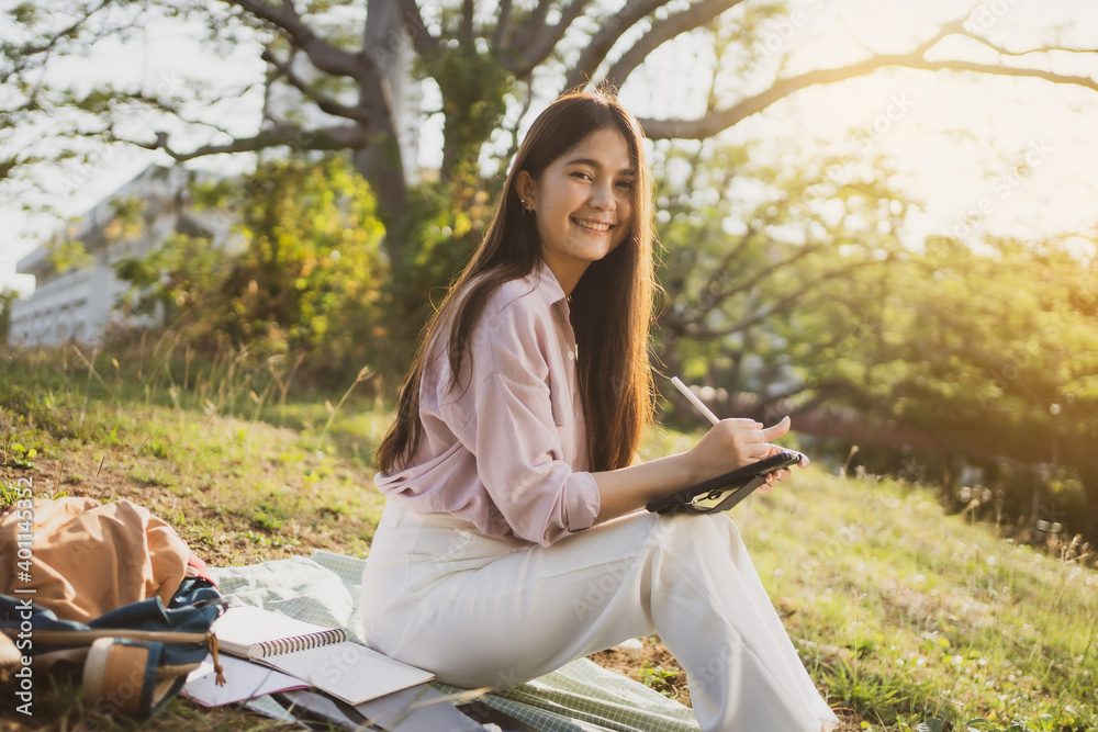 Asian female students studying online She is sitting outdoors