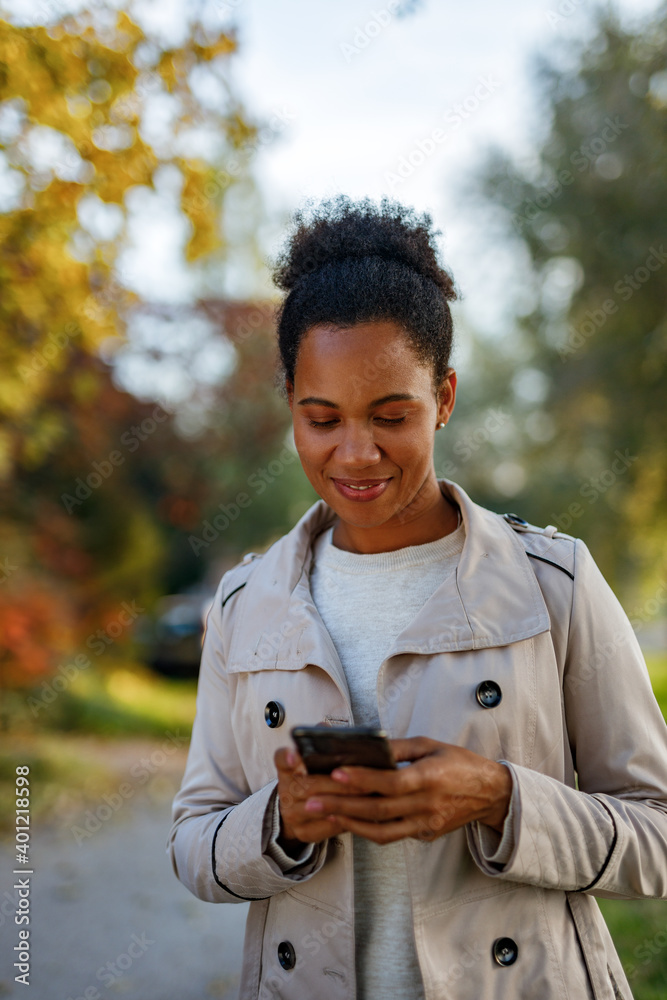 Woman using mobile phone, while walking outside.