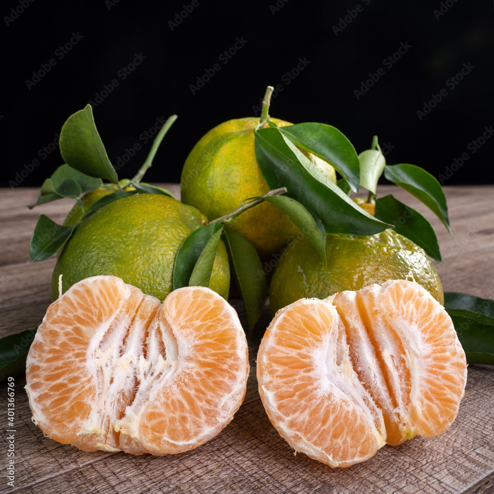 Fresh green tangerine mandarin orange on dark wooden table background.